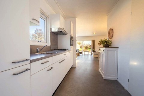 Moderne Lodge-Küche mit weißen Schränken im Vordergrund und hellem Wohnbereich im Hintergrund.
