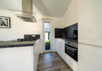Cucina moderna in una lodge con mobili bianchi, piano nero, forno, piano a gas e ampia finestra.