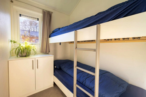 Gemütliches Zimmer in einer Lodge mit Etagenbetten, blauer Bettwäsche, Schrank und Fenster.