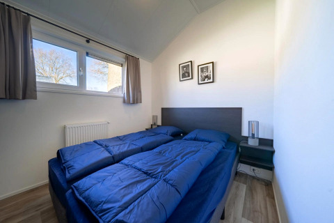 Modernes Schlafzimmer in einer Lodge mit zwei Einzelbetten, blauer Bettwäsche und Wanddekoration.