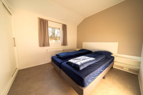 Helles, modernes Schlafzimmer in einer Lodge mit zwei Einzelbetten, Fenster und schlichter Dekor.