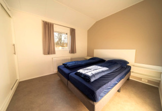 Helles, modernes Schlafzimmer in einer Lodge mit zwei Einzelbetten, Fenster und schlichter Dekor.