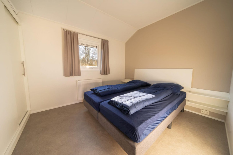 Dormitorio moderno y luminoso en una cabaña, con dos camas individuales y ventana con cortinas.