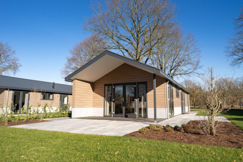 Moderne lodge Velthorst 6 bij Zuiderzee in Nederland, met terras, tuin en heldere blauwe lucht.