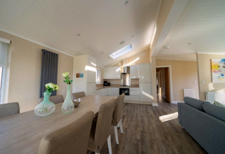 Moderne lodgewoonkamer met open keuken, grote eettafel, comfortabele stoelen en veel natuurlijk licht.