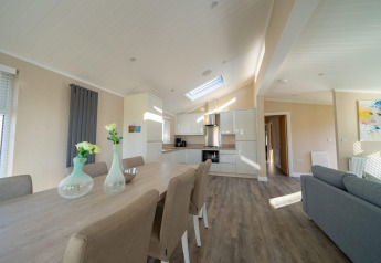 Moderne lodge met open keuken, eetgedeelte, stijlvolle stoelen en een gezellig, licht ingerichte zitruimte.