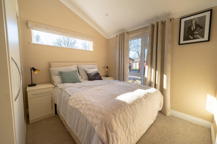 Bright bedroom at a lodge, featuring a modern decor, double bed, and large windows offering a view.