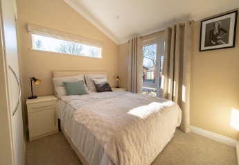 Dormitorio luminoso en una cabaña, con decoración moderna, cama doble y grandes ventanas con vista.