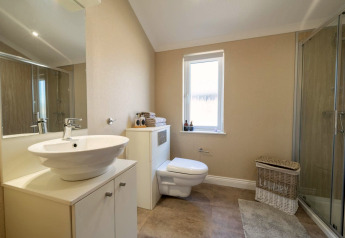 Bagno moderno di un lodge con wc sospeso, box doccia, lavabo rotondo e cesto portabiancheria in vimini.