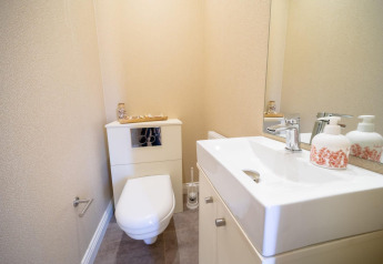 Beeld van een hedendaags, compact toilet in een lodge met zwevend toilet, wastafel en spiegel.