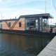 Moderne husbåd ved kajen, Waterlodge 4, Zuiderzee, Holland, med træbeklædning og store vinduer.