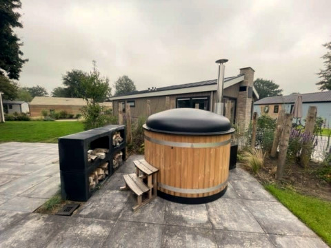 Houten hottub met zwart deksel bij Hackfort Hottub 6 op Zuiderzee, Nederland, buiten op het terras.