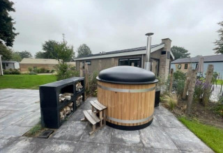 Bañera de hidromasaje de madera con tapa negra en Hackfort Hottub 6 en Zuiderzee, Países Bajos, al aire libre.