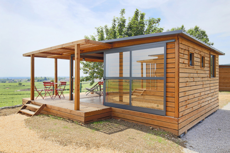 Cabaña moderna de madera Chalet Evasion Vista Vue Vignes con pared de cristal y terraza con vistas al campo.