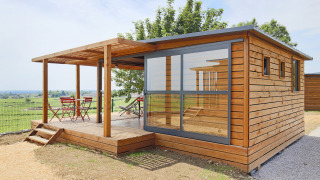 Cabaña moderna de madera Chalet Evasion Vista Vue Vignes con pared de cristal y terraza con vistas al campo.