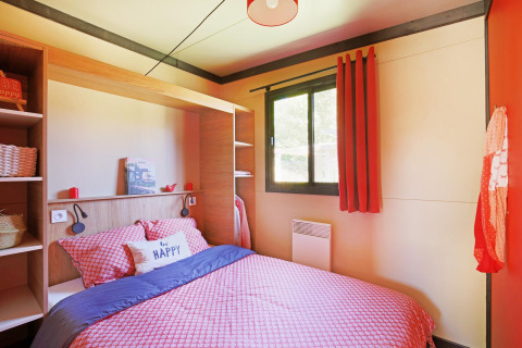 Knusse slaapkamer met rood beddengoed, groot raam en 'be happy' kussen in Chalet Evasion Vista Vue Vignes.