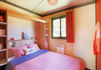 Knusse slaapkamer met rood beddengoed, groot raam en 'be happy' kussen in Chalet Evasion Vista Vue Vignes.