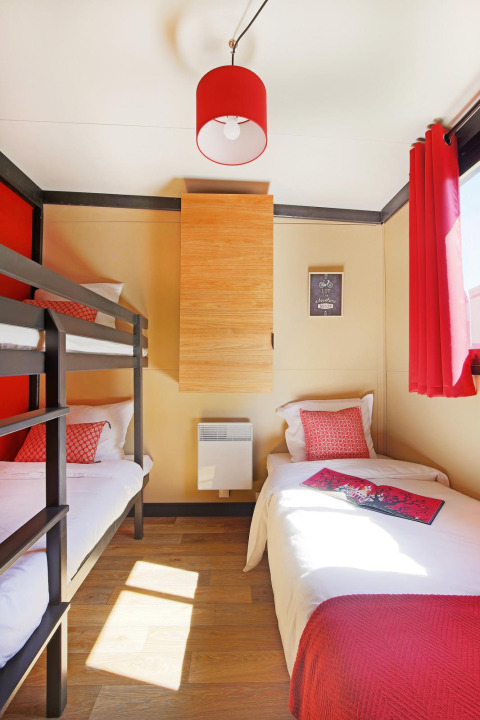 Dormitorio luminoso en Chalet Evasion Vista Vue Vignes en Huttopia Meursault, Francia, con cama litera e individual.