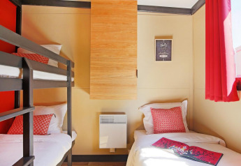 Helles Zimmer im Chalet Evasion Vista Vue Vignes bei Huttopia Meursault, Frankreich, mit Etagenbett und Einzelbett.
