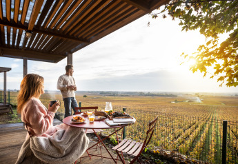 Coppia fa colazione sulla terrazza dello Chalet Evasion Vista Vue Vignes con vista sui vigneti a Meursault, Francia.
