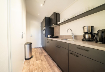 Cucina moderna nera con macchina da caffè e pattumiera a Berkel 4, De Utrechtse Heuvelrug, Paesi Bassi.