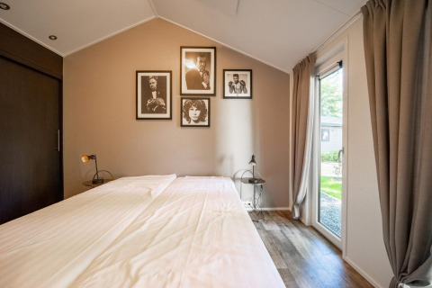 Slaapkamer in Berkel 4-lodge op De Utrechtse Heuvelrug, Nederland, met tweepersoonsbed en wanddecoratie.