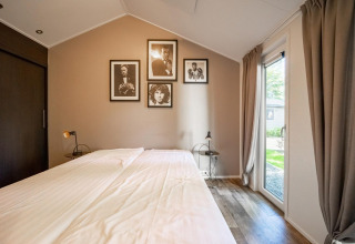 Slaapkamer in Berkel 4-lodge op De Utrechtse Heuvelrug, Nederland, met tweepersoonsbed en wanddecoratie.