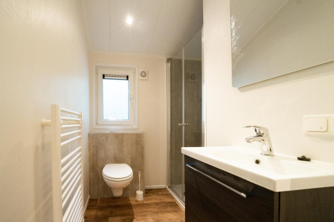 Moderne badkamer bij Berkel 4 in De Utrechtse Heuvelrug, Nederland, met douche, wastafel en hangtoilet.