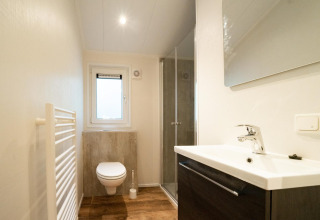 Moderne badkamer bij Berkel 4 in De Utrechtse Heuvelrug, Nederland, met douche, wastafel en hangtoilet.