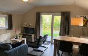 Sala en Boslodge 4 en De Utrechtse Heuvelrug, Países Bajos, con decoración moderna y vista al jardín.