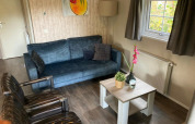 Sala de estar en Boslodge 4 en De Utrechtse Heuvelrug, Países Bajos, con sofá azul y sillones modernos.