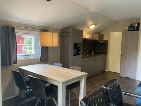 Interior of Boslodge 4 at De Utrechtse Heuvelrug, Netherlands, featuring dining table and kitchenette.