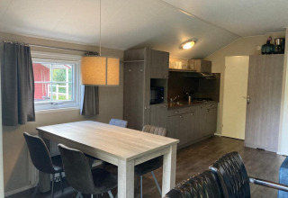 Interior de Boslodge 4 en De Utrechtse Heuvelrug, Países Bajos, con mesa de comedor y cocina pequeña.