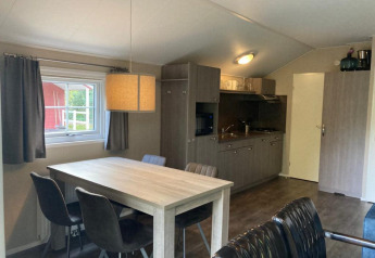 Indretning af Boslodge 4 på De Utrechtse Heuvelrug, Holland, med spisebord og tekøkken.