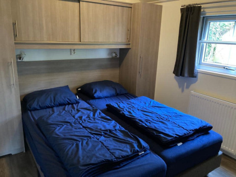 Dormitorio en Boslodge 4 en De Utrechtse Heuvelrug, Países Bajos, con dos camas individuales y ropa de cama azul.