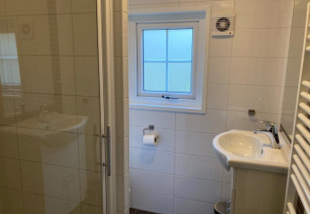 Modernes Badezimmer in Boslodge 4 bei De Utrechtse Heuvelrug, Niederlande, mit Waschbecken, Dusche und Fenster.