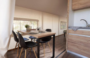 Zona de comedor y cocina en Glampingtent 6 en De Utrechtse Heuvelrug, con mesa y sillas modernas.
