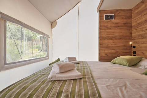 Indvendigt billede af Glampingtent 6 på De Utrechtse Heuvelrug, med komfortabel dobbeltseng og vinduer.