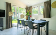 Dining area in a lodge with a modern black table, six chairs, large windows, and a scenic outdoor view.