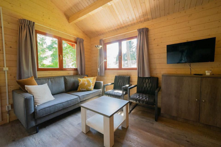 Woonkamer in tiny house Boekhorst 4 op De Utrechtse Heuvelrug, Nederland, met bank, stoelen en tv.