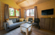 Woonkamer in tiny house Boekhorst 4 op De Utrechtse Heuvelrug, Nederland, met bank, stoelen en tv.