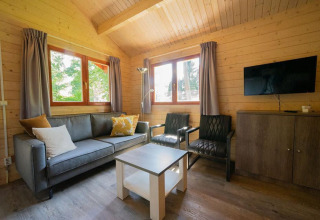 Woonkamer in tiny house Boekhorst 4 op De Utrechtse Heuvelrug, Nederland, met bank, stoelen en tv.