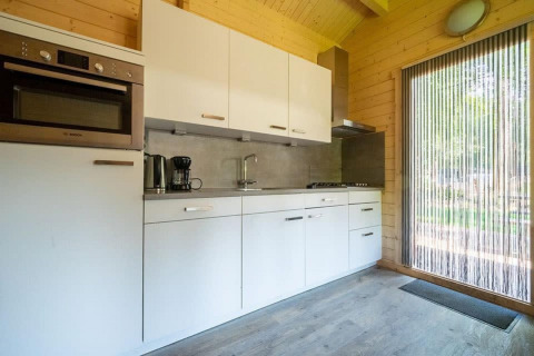 Cocina moderna y compacta en la tiny house Boekhorst 4, De Utrechtse Heuvelrug, Países Bajos, con acabado de madera.