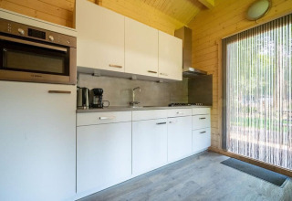 Moderne en compacte keuken in tiny house Boekhorst 4 op De Utrechtse Heuvelrug, Nederland, met houtafwerking.