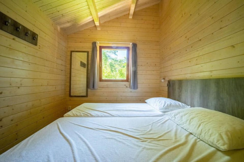 Dormitorio en una tiny house con paredes de madera y dos camas individuales, Boekhorst 4, De Utrechtse Heuvelrug, Países Bajos.