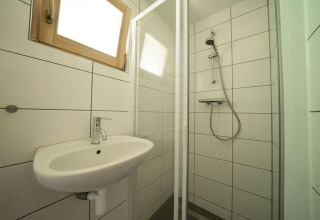 Kleine badkamer in Boekhorst 4 bij De Utrechtse Heuvelrug, met douche, wastafel en raam.