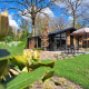 Moderne lodge Hackfort 4 ved De Utrechtse Heuvelrug i Holland, omgivet af grønne træer og solrig have.