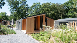 Panorama Cottage 4, lodge à façade bois moderne, entouré de verdure et d'autres chalets dans la nature.