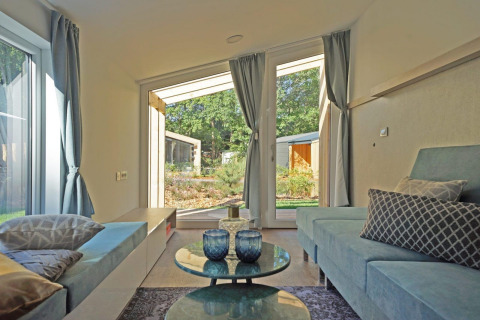 Modernes Wohnzimmer im Panorama Cottage 4 bei De Utrechtse Heuvelrug, Niederlande, mit Blick nach draußen.