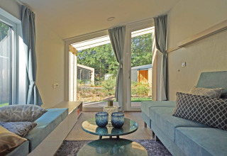 Salón moderno en Panorama Cottage 4 en De Utrechtse Heuvelrug, Países Bajos, con vistas al jardín exterior.